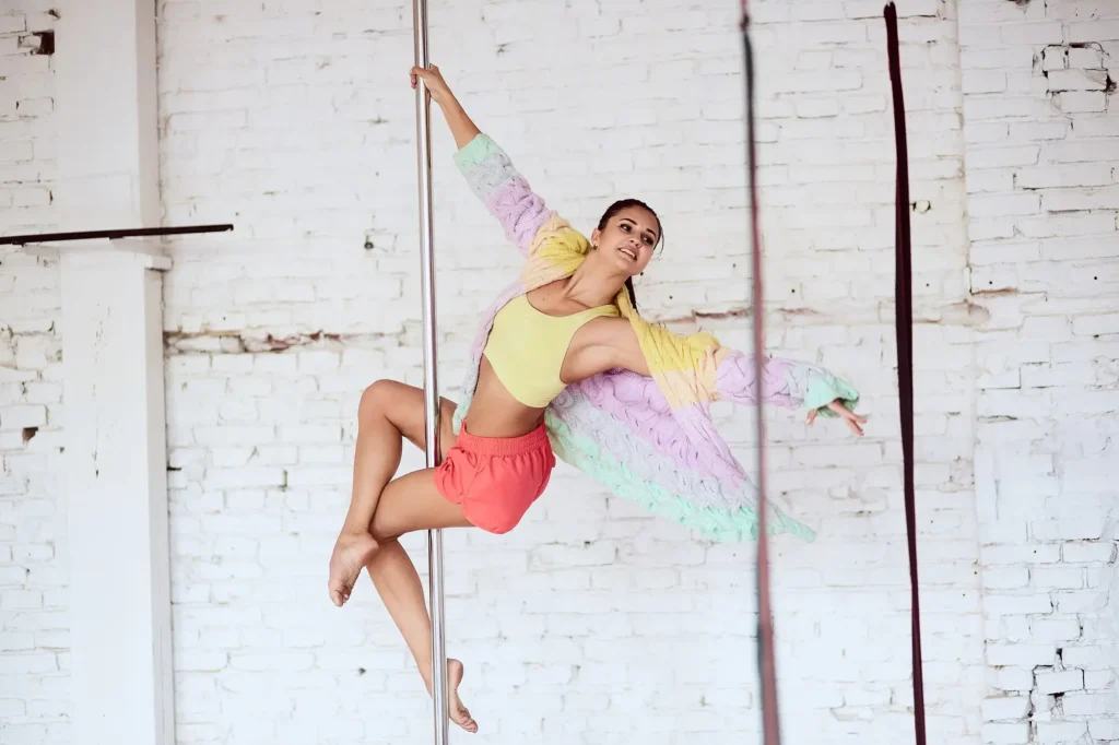 Kobieta uprawiająca pole dance - taniec na rurze wykonująca figurę pole dance w pole dance studio