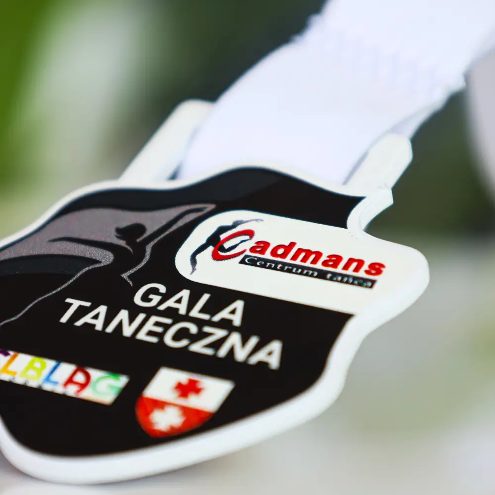 Zbliżenie na falowaną krawędź białego medalu akrylowego z nadrukiem cyfrowym dla tancerzy, nowoczesne pamiątki okolicznościowe i trofea sportowe od producenta nagród.
